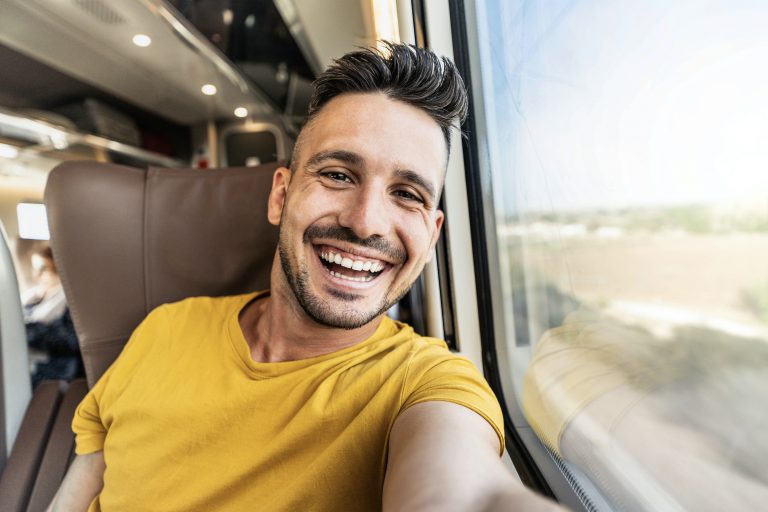 Happy male tourist taking selfie sitting in the train - Transportation, tourism and travel concept